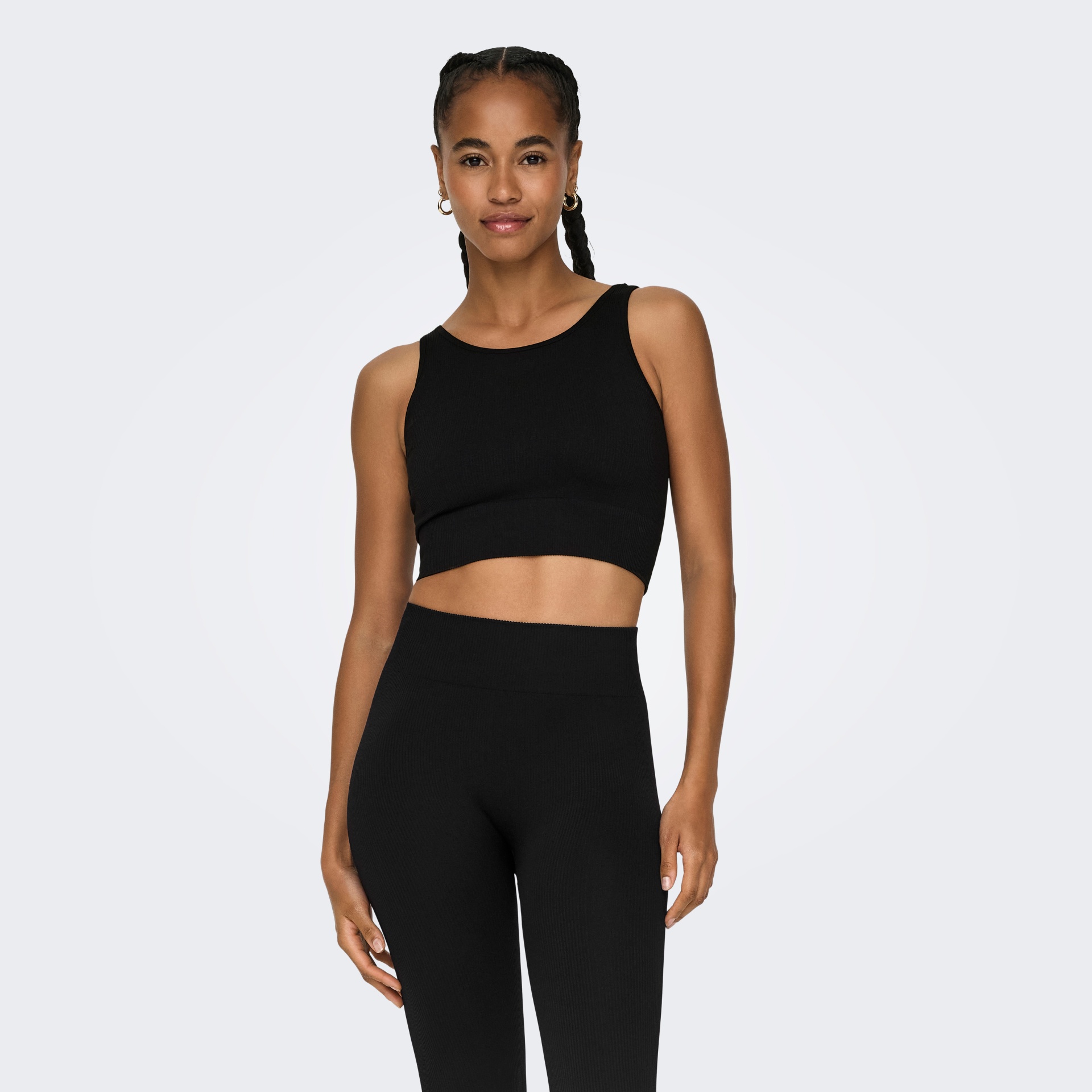 Mulher com conjunto desportivo preto composto por top cropped e calças justas.