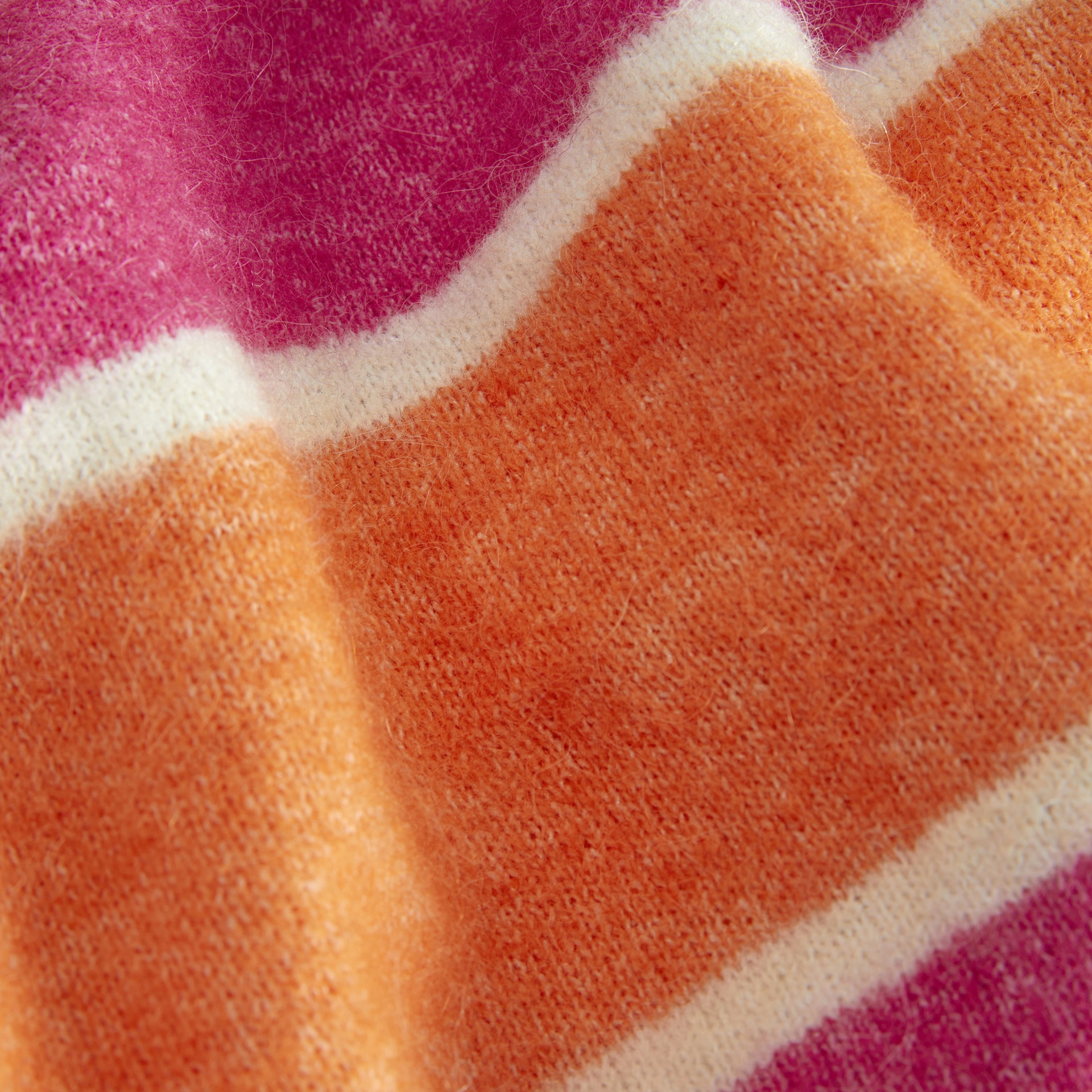 Detalhe de tecido com riscas laranja, creme e rosa púrpura