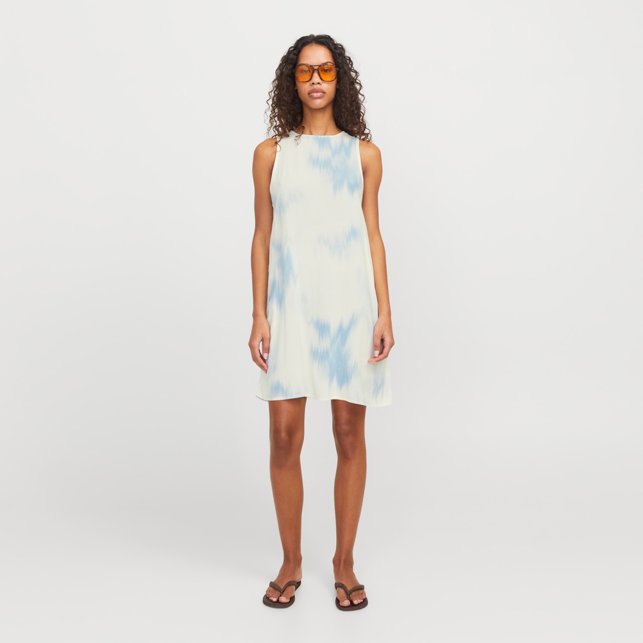 Vestido feminino tie-dye azul claro e branco com sandálias pretas e óculos de sol laranja