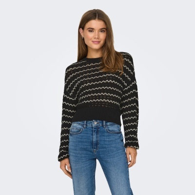 Mulher a usar camisola preta com padrão branco e jeans azul