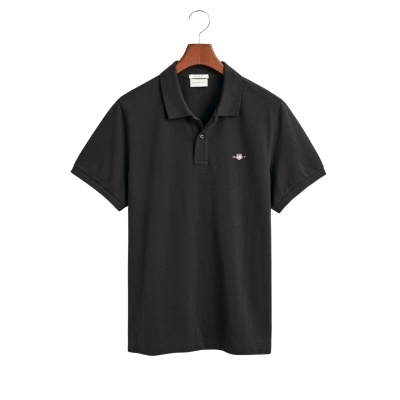 Polo preto GANT de algodão com logótipo bordado no peito pendurado numa cabide de madeira