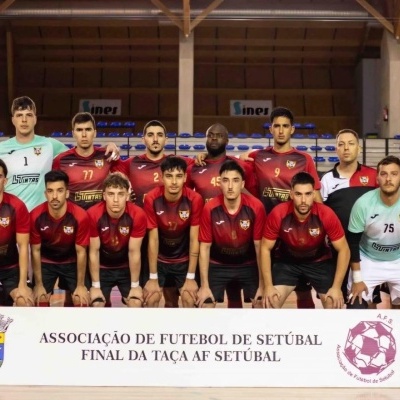 Desportop.pt e Futebol Clube São Francisco: Dois Anos de Parceria de Sucesso! Equipa de futebol masculina posando em pavilhão com faixa da Associação de Futebol de Setúbal