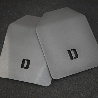 Dois coletes balísticos cinzentos com letra D preta sobre superfície escura
