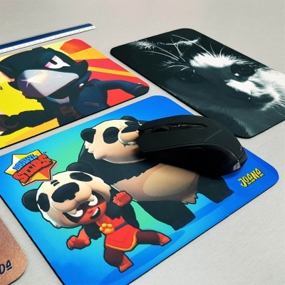 Três tapetes de rato coloridos com diferentes desenhos e um rato preto em cima de um deles