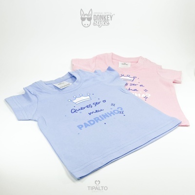 Duas t-shirts infantis azul e rosa com textos sobre padrinhos e madrinhas