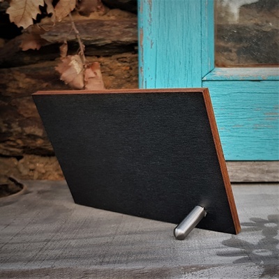 Placa preta de madeira com suporte metálico junto a janela azul envelhecida