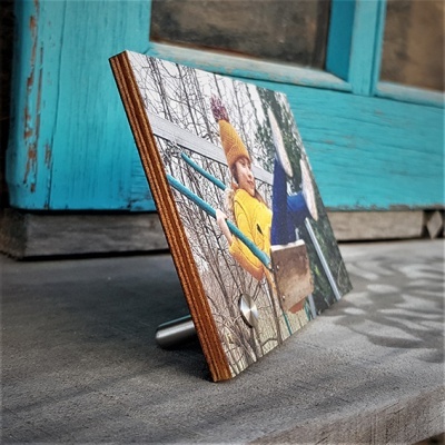 Painel de madeira com foto de criança no baloiço em suporte metálico