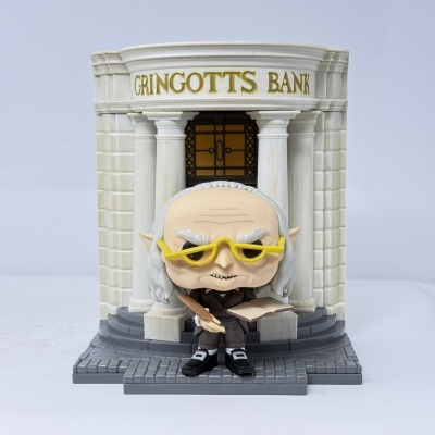 Figura Funko Pop de personagem com óculos amarelos e banco Gringotts em miniatura