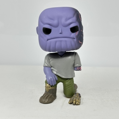 Figura de vinil de personagem roxo com roupa cinza e verde e mão dourada no chão