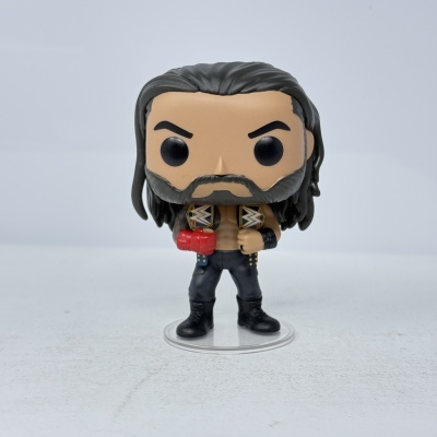 Figura Funko Pop de lutador com cabelo e barba castanha, calças pretas e luva vermelha, segurando cintos da WWE