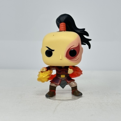 Figura Funko Pop com cicatriz vermelha, cabelo preto e fogo nas mãos, vestida com uniforme vermelho e castanho
