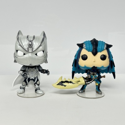 Dois bonecos Funko Pop, um prateado e outro azul e preto com lança amarela.