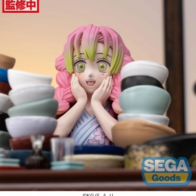 Estátua de personagem anime com cabelo rosa e verde e taças empilhadas à frente