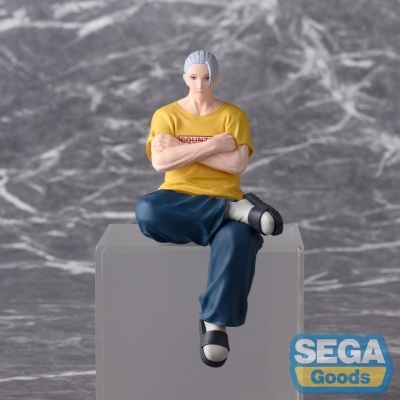 Estátua de personagem masculino com camisa amarela, calças azuis e sandálias, sentada numa caixa transparente com logo SEGA Goods