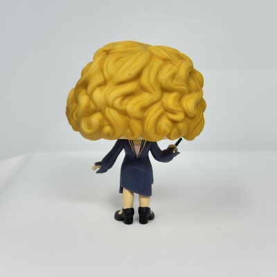 Figura colecionável com cabelo amarelo encaracolado e vestido azul de costas