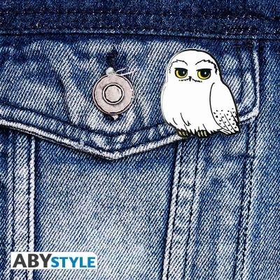 Alfinete de coruja branca num bolso de ganga azul