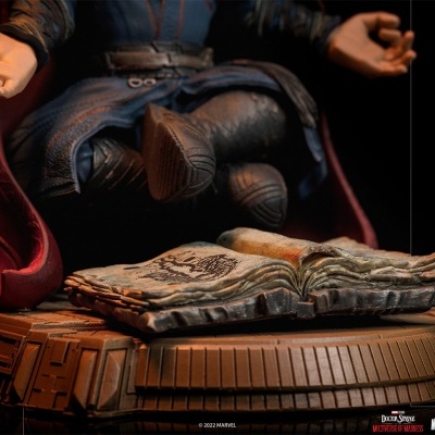 Figura colecionável com livro aberto e base decorativa em tons castanhos