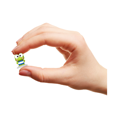 Mão segurando pequena figura de sapo verde com roupa azul e branca