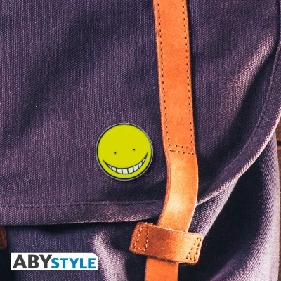 Mochila roxa com alça castanha e pin amarelo sorridente