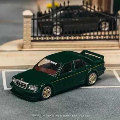Miniatura de carro desportivo verde escuro com spoiler, jantes douradas numa vaga de estacionamento