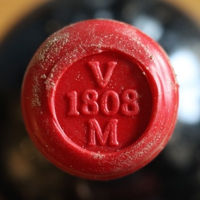 Tampa vermelha com inscrição V 1808 M coberta de poeira.