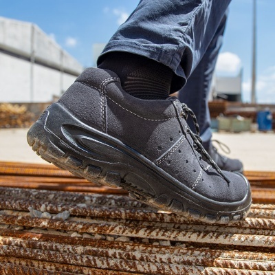 Ténis de segurança pretos com sola grossa antiderrapante em ambiente industrial