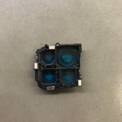 Peça eletrónica preta com quatro lentes circulares azuis em superfície cinza