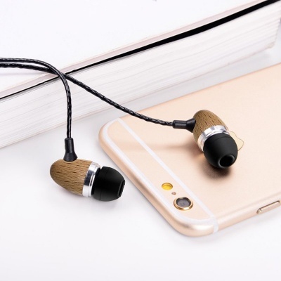 Auriculares de madeira com cabo preto junto a smartphone dourado