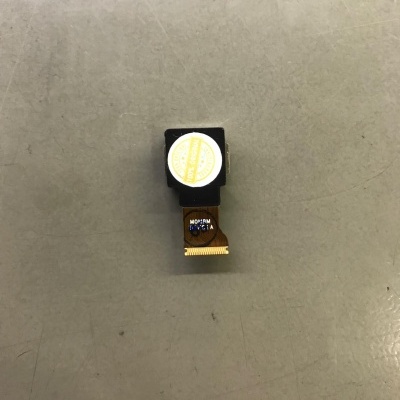 pequena câmara eletrónica com fita flexível sobre superfície cinzenta