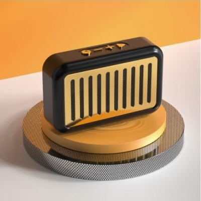 Coluna sonora portátil preta e dourada sobre bases redondas dourada e prateada