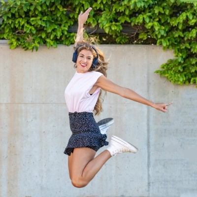 Mulher a saltar com saia preta de padrão branco e t-shirt rosa claro