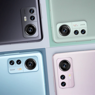 Quatro smartphones coloridos com câmeras traseiras visíveis em fundo branco