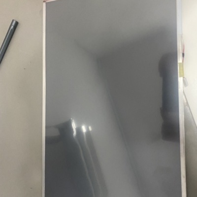 Ecrã retangular grande com moldura fina prateada sobre superfície cinzenta com fita amarela