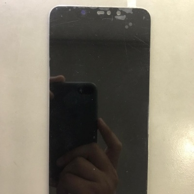 Ecrã de smartphone preto com manchas e riscos sobre superfície branca