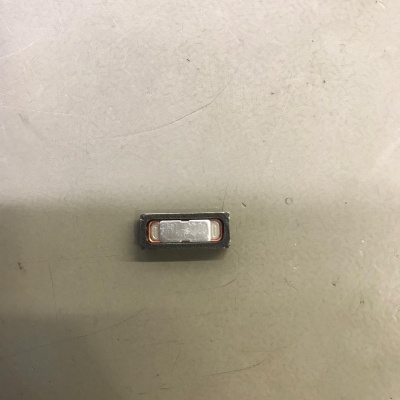 Componente eletrónico retangular preto e prata sobre superfície clara