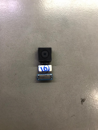 Módulo de câmara preto com conector flexível numa superfície cinzenta