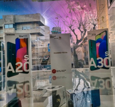 Caixas de telemóveis Samsung A20s, A30s e Huawei P30 lite em exposição sobre superfície refletora