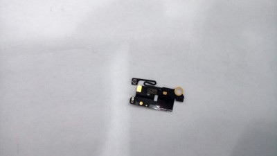 Peça eletrónica pequena preta com componentes dourados sobre fundo branco