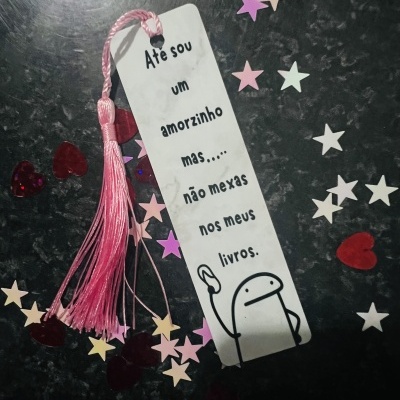 Marcador de páginas branco com tassel rosa e confetes coloridos numa superfície escura