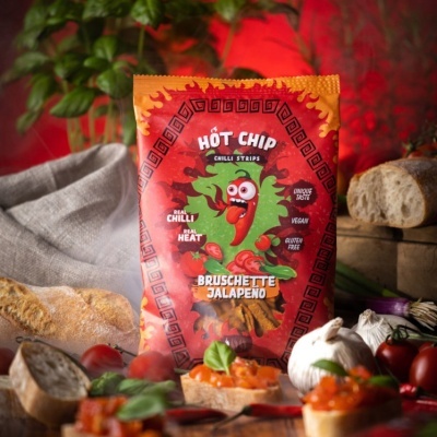 Pacote de snacks Hot Chip Chilli Strips Bruschette Jalapeno em meio a ingredientes frescos sobre mesa