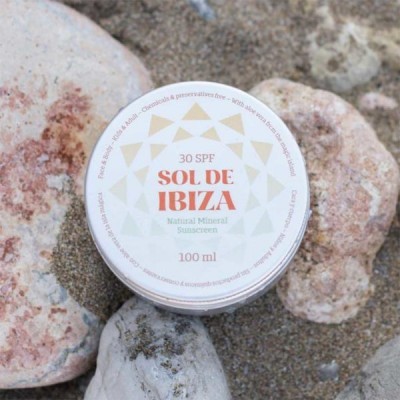 Frasco branco com protetor solar Sol de Ibiza sobre areia e pedras