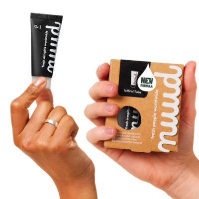Mãos seguram desodorizante natural em creme da marca mudd com embalagem de cartão castanho.