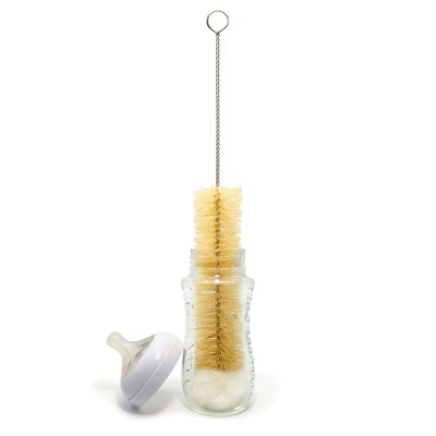 Escova de limpeza para biberão dentro de um biberão de vidro com tetina ao lado