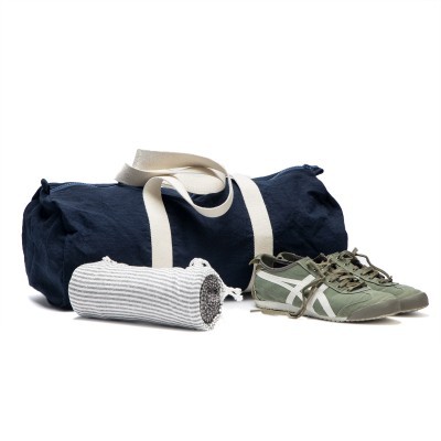 Saco desportivo azul, toalha branca riscada e sapatilhas verdes com detalhes brancos