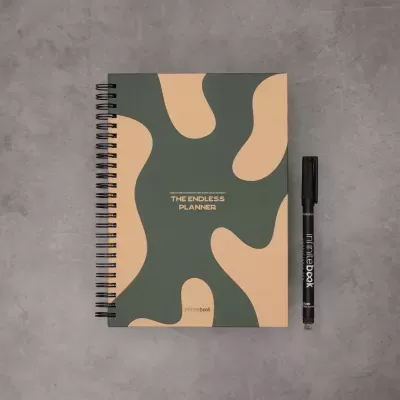 Caderno espiralido verde e bege com caneta preta sobre superfície cinzenta