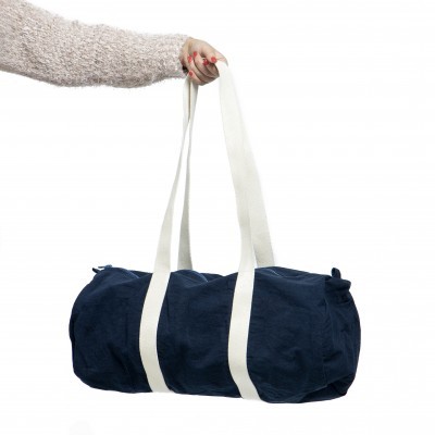 Mala desportiva azul escura com tiras brancas sendo segurada