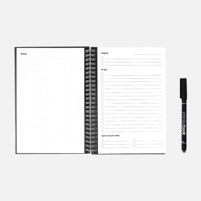 Caderno de espiral aberto com caneta preta ao lado sobre fundo branco