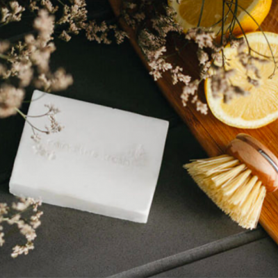 Sabonete branco com escova de madeira, limão cortado e flores secas