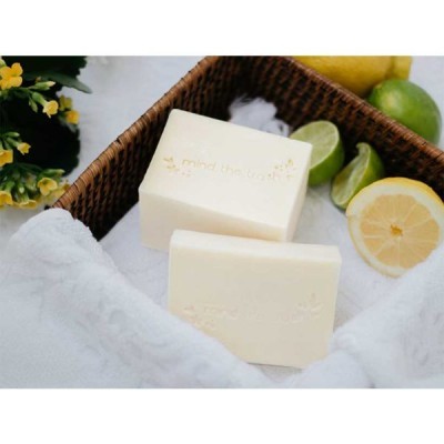 Dois sabonetes brancos numa cesta de vime com frutas cítricas e flores amarelas