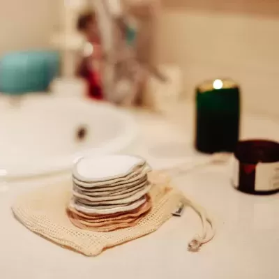 Discos reutilizáveis em algodão empilhados sobre saco de rede em casa de banho